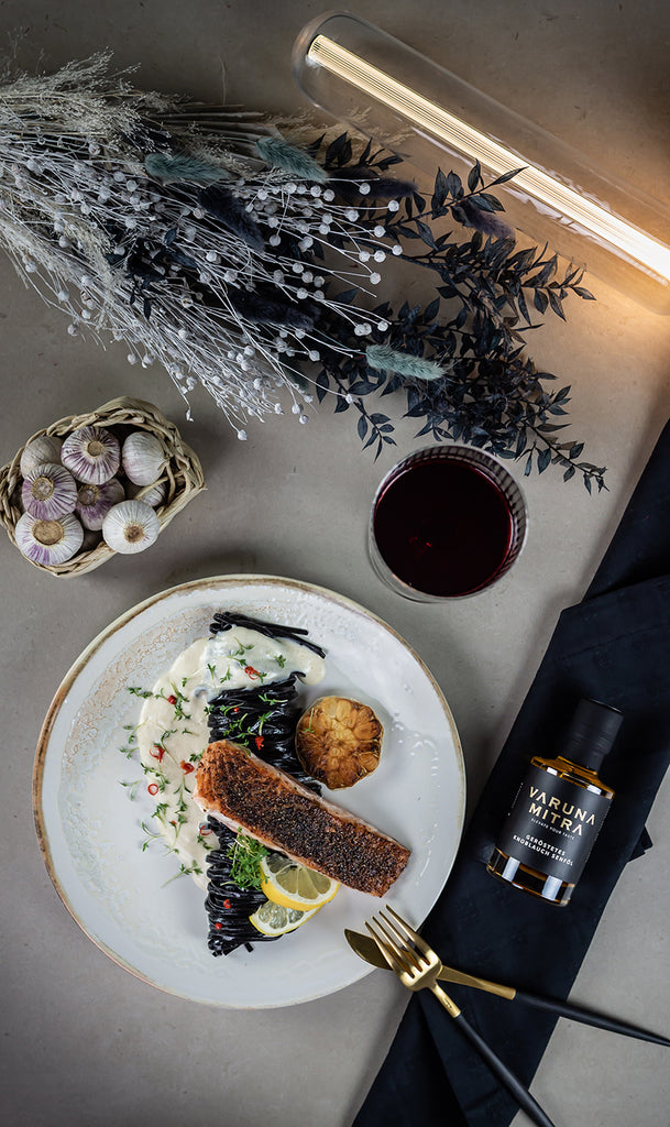 Geröstetes Knoblauch Würzöl mit Lachs, Pasta und Rotwein von oben fotografiert 