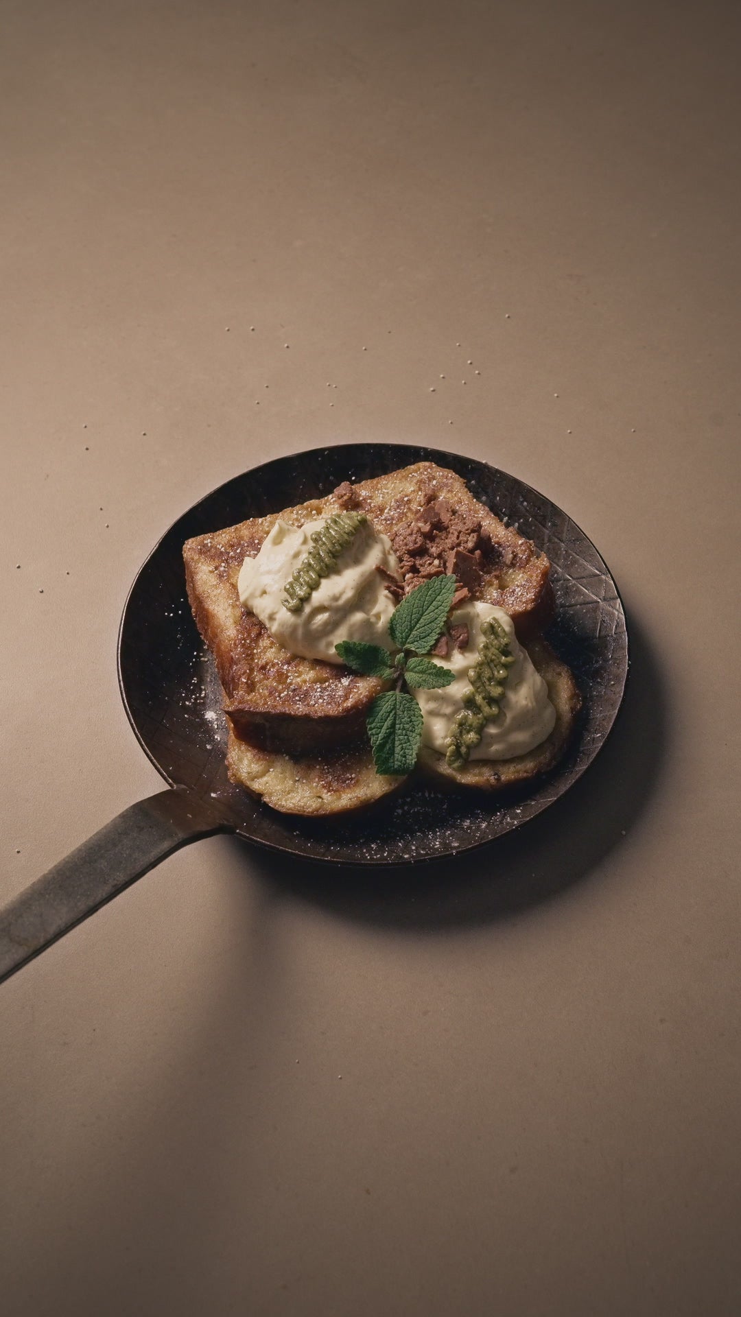 Rezept French Toast mit Kaffeeöl und Kaffee Mascarpone, verziert mit Pistazien Creme und Minze in einer Eisenpfanne auf hellem Stein.