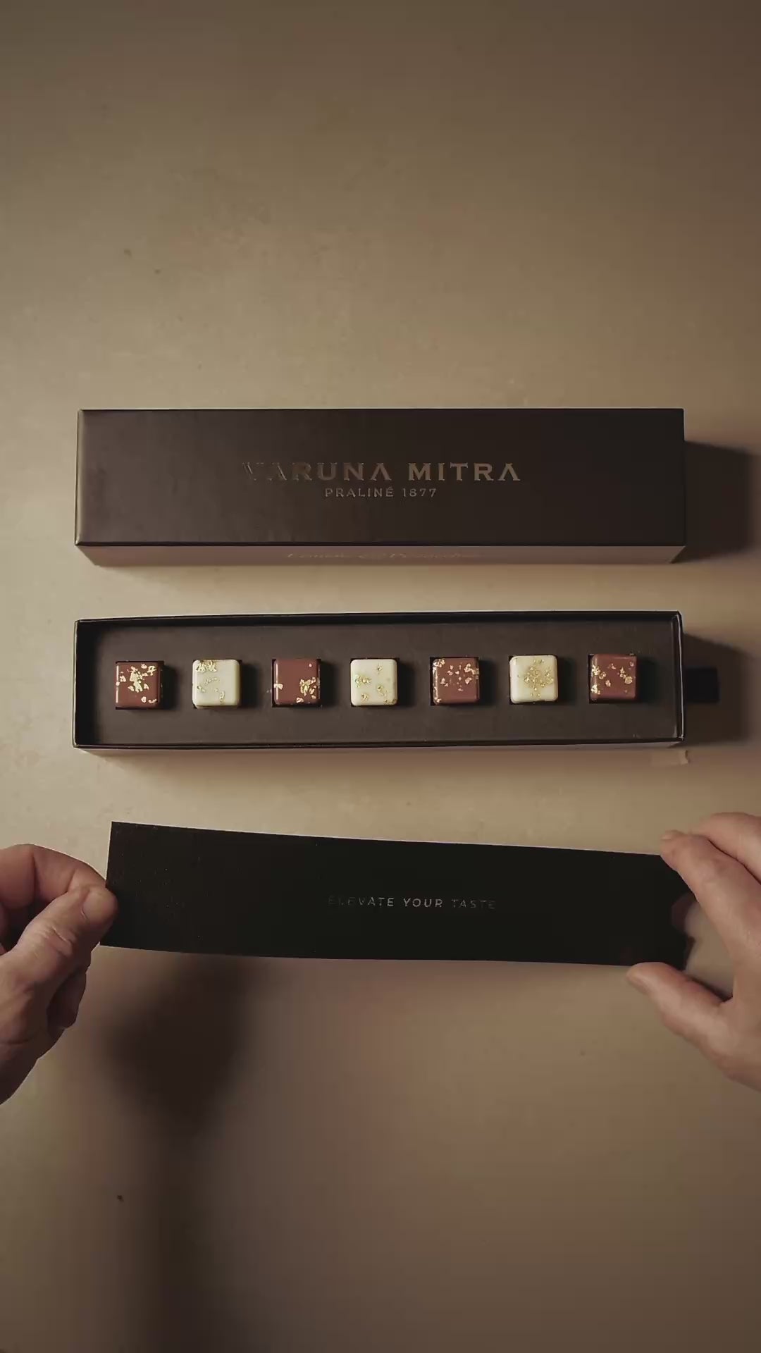 Varuna Mitra Pralinen Geschenkbox auf beigem Hintergrund, gefüllt mit Zitrone-Pistazie und Kaffee-Karamell Praline.