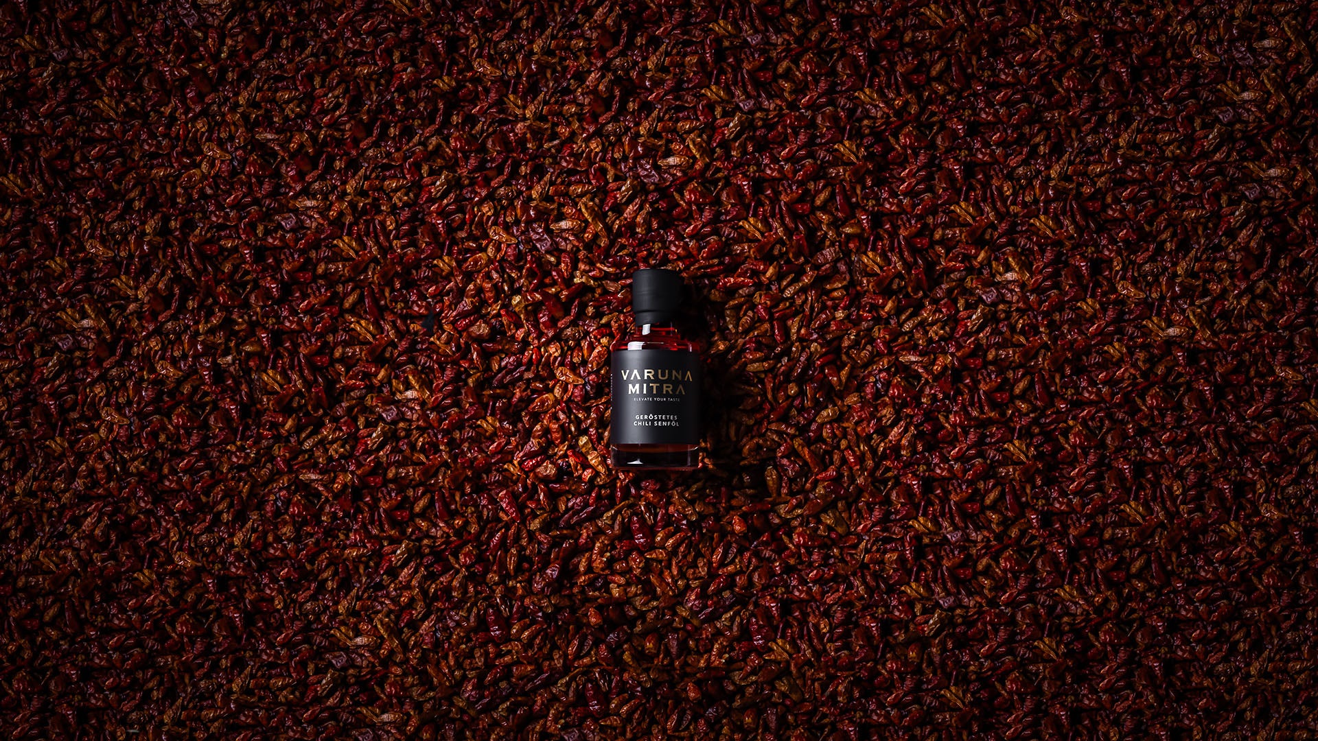 Varuna Mitra Chili Oel Flasche auf einem Meer von Bird's Eye Chilis