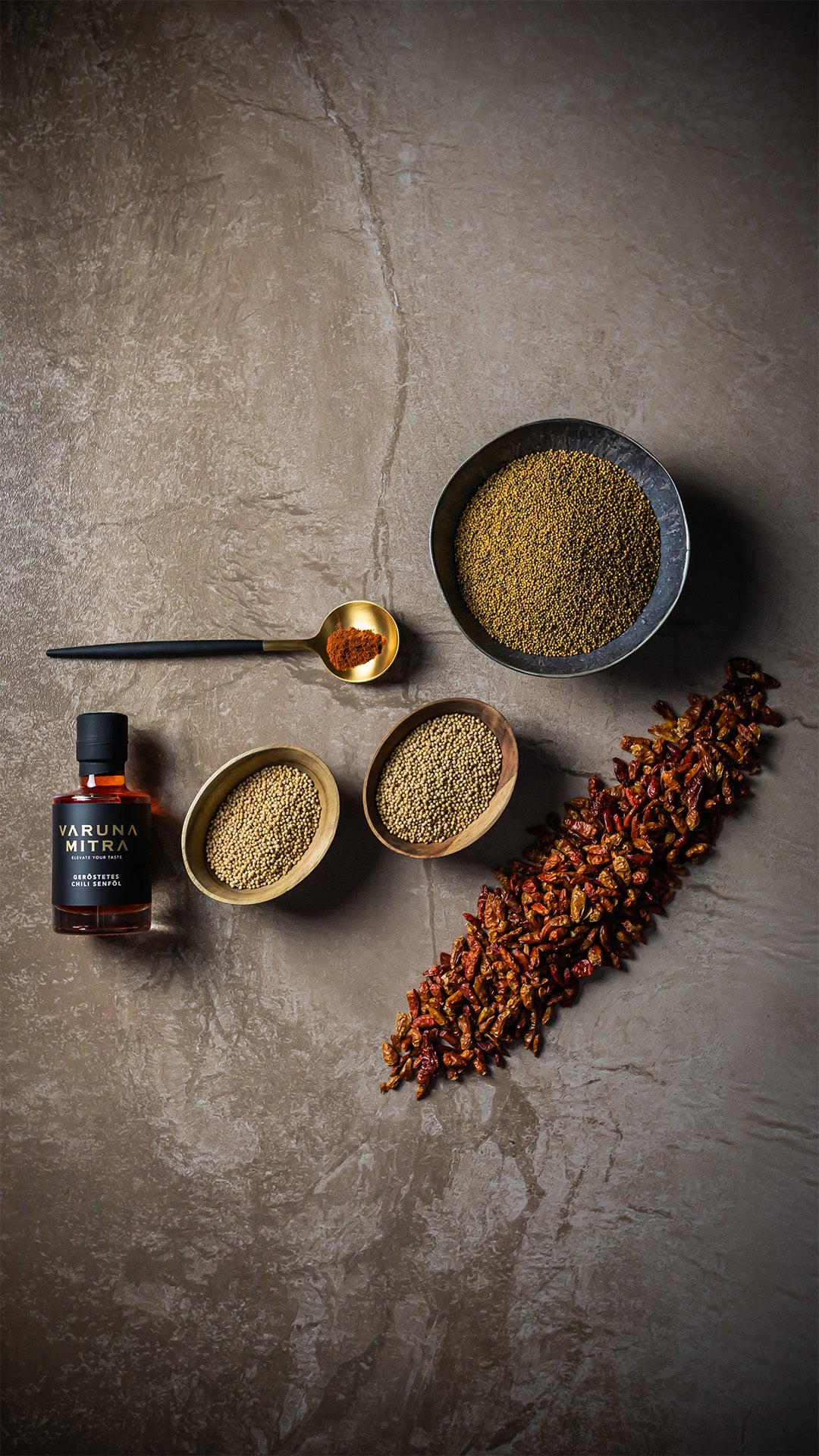 Varuna Mitra Chili Oel, Senfsaat in verschiedenen Schüsseln, Chilipulver in einem goldenen Löffel und Bird's Eye Chilis.