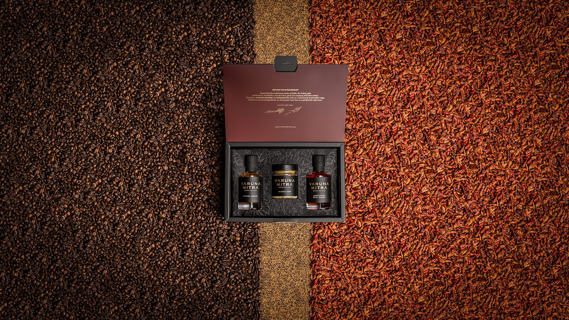 Varuna Mitra Geschenkbox Varuna mit zwei Ölen und einem Senf auf einem Bett aus Kaffeebohnen, Chilis und Senfsaat.