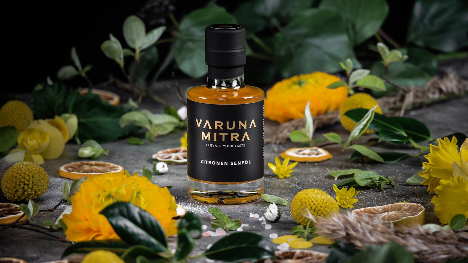 Varuna Mitra Zitronenöl umgeben von getrockneten Zitronenscheiben, Blüten und Blättern.