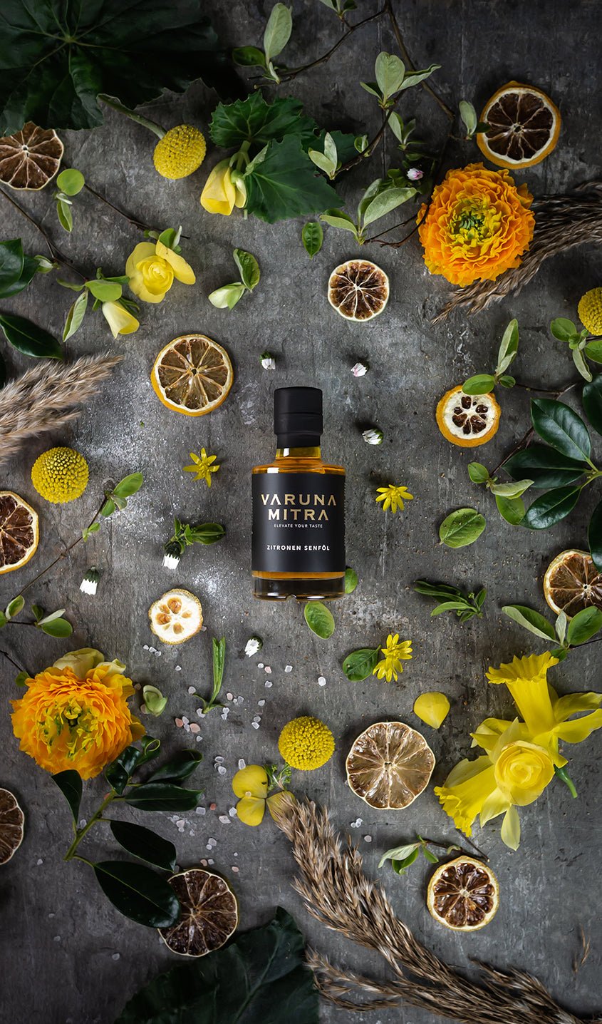 Varuna Mitra Zitronenöl Flasche umgeben von getrockneten Zitronenscheiben und Blüten.